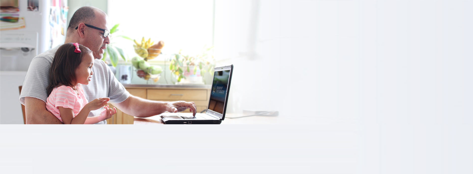 Father doing online school work with daughter on lap